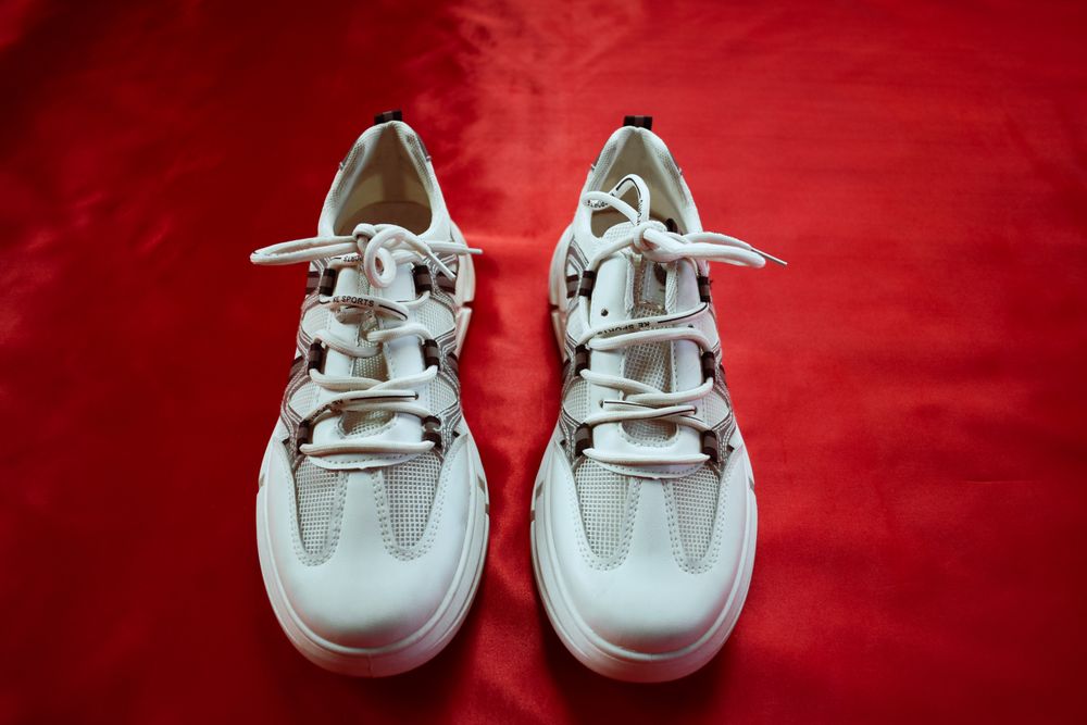 Saubere weiße Sneaker vor rotem Hintergrund